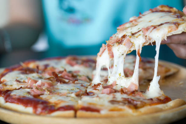 istock Close up af a hot pizza slice with dripping ham sausage and mozzarella cheese. 926877464