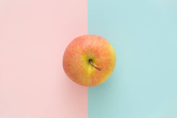 istock One delicious apple on rose quartz and serenity blue background. Directly above view. 926877536