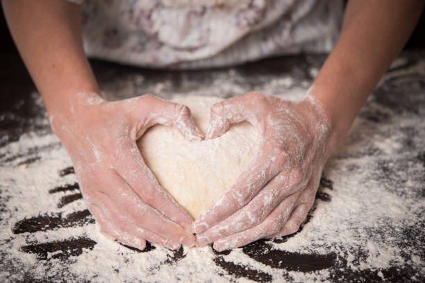 Cooking with love. Female hands holding dough in heart shape
