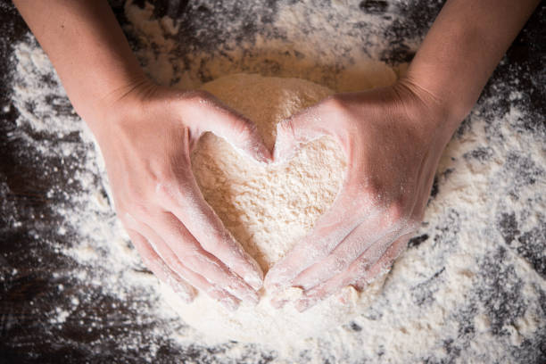 mani femminili che tengono l'impasto a forma di cuore - bread making foto e immagini stock