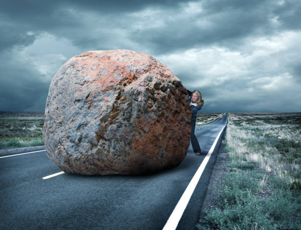 istock Businesswoman Pushes Large Stone Down Rural Highway 926885936