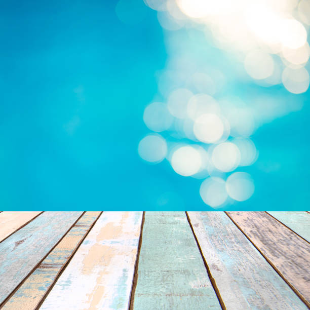 istock Perspective wood table top and Soft focus bokeh light effects over a rippled, blue water background in the pool, product display montage 926901866