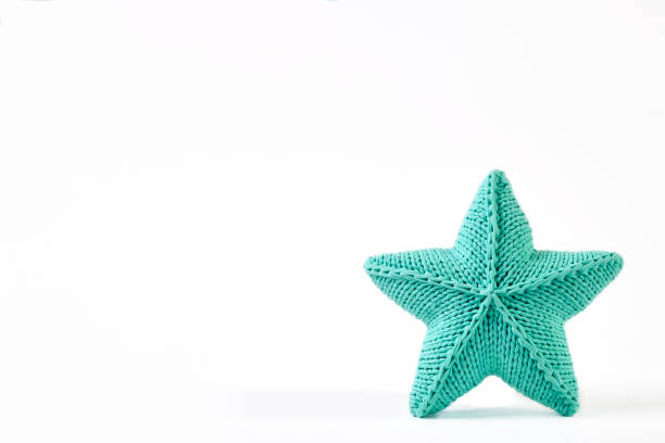 Blue-green knitted five-pointed star shaped pillow on white background