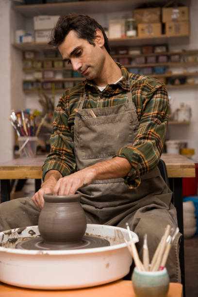 istock Artist makes clay pottery on a spin wheel in workshop 926917250