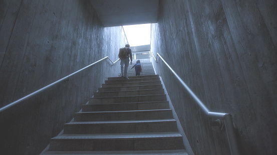 father and son climbing stairs in pedestrian subway, going to the city. Concept of family in town