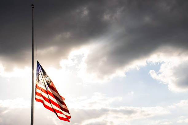 Perfect American Flag lowered to Half-Mast waving in the wind fully extended after another sad memorial stock photo