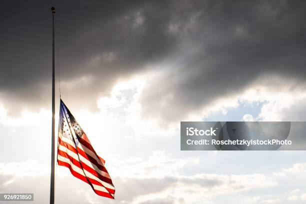 Perfect American Flag Lowered To Halfmast Waving In The Wind Fully Extended After Another Sad Memorial Stock Photo - Download Image Now