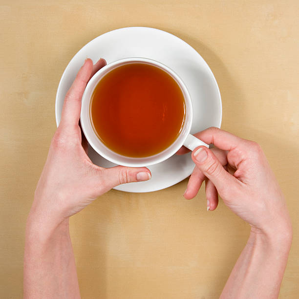 female hands holding a cup of tea on wood table stock photo