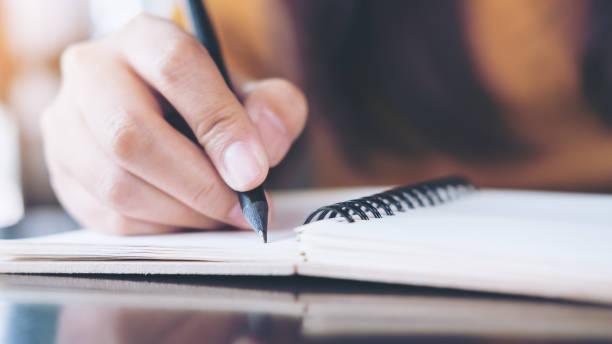 istock Close up image of woman's hand writing on notebook with wooden table background 926944160