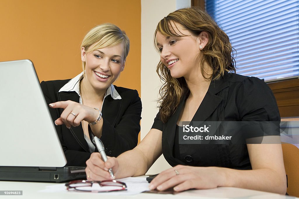 Two Women Female Office Teamwork With Computer Two attractive young female executives working together on a laptop Adult Stock Photo