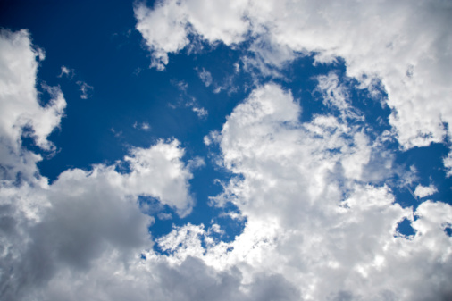 Single cumulus cloud in plain blue sky, vertical, large copy space.
