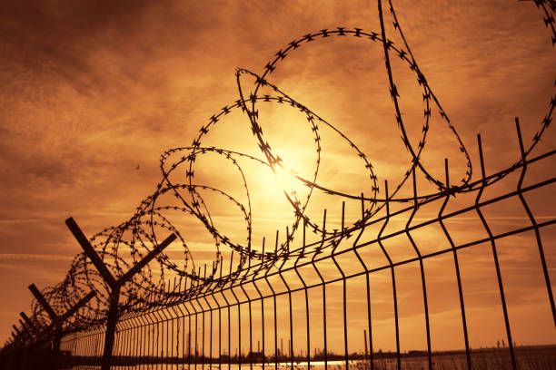 istock Prison barbed wire fence at sunset 926962546