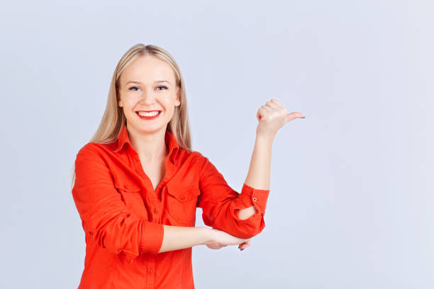 istock Young blond woman , with positive emotions points to a gray back 926970990