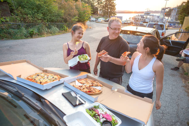 famiglia che ha pizza e insalata picnic nella lineup dei traghetti - car family picnic vacations foto e immagini stock