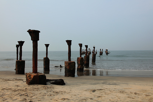 Old ruined sea piers with white herons sitting on it in Calicut beach in Kerala, India