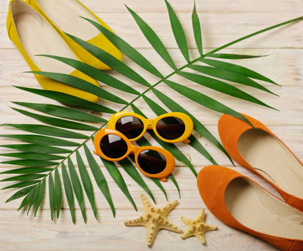 Beach accessories - sunglasses, hat and shoes orange and yellow color with tropical palm leaves wooden background with empty space for text. Flat lay. Beach accessories - sunglasses, hat and shoes orange and yellow color with tropical palm leaves wooden background with empty space for text. Flat lay, top view. shell starfish orange sea stock pictures, royalty-free photos & images