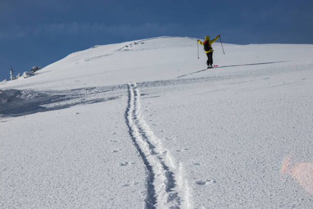 istock Woman on skis with raised arms climbing in snow 927031888