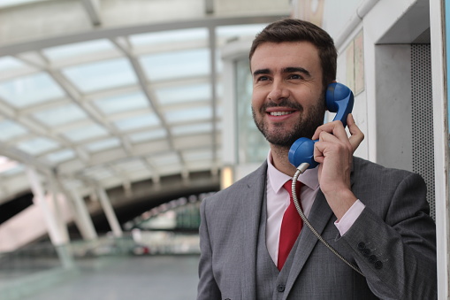 Businessman calling by public phone at the airport.
