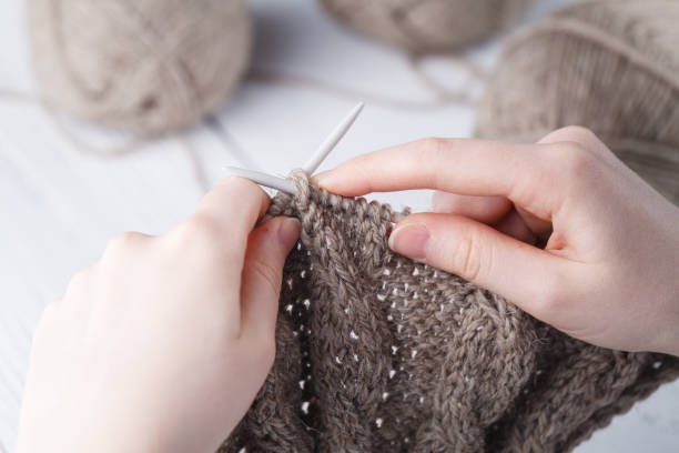 istock Young woman crochets a warm blanket with beige wool 927038624