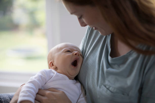 istock Redhead mother looking at yawning newborn son 927039816