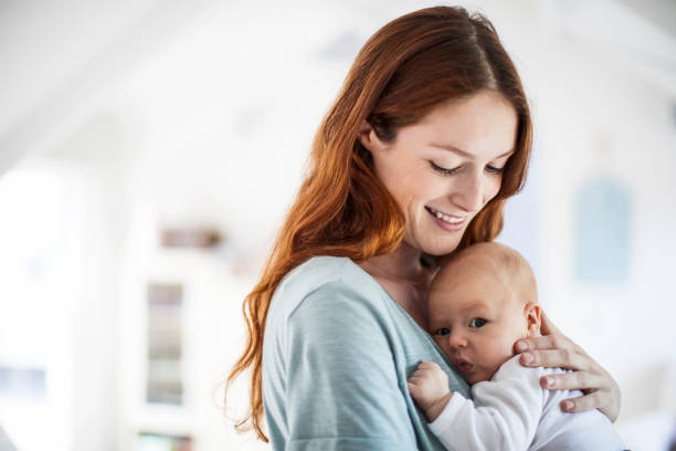 istock Smiling redhead mother carrying son at home 927039976