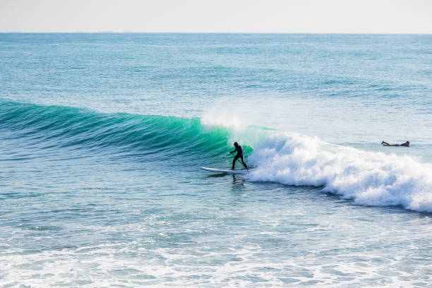 istock Surfer on stand up paddle board on blue wave. Winter surfing in ocean 927043306