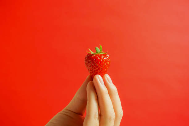 A strawberry and hand. Eating a strawberry.