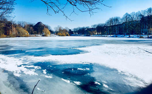 Tree branches covered with frost and snow hanging over a river - misty winter day landscape