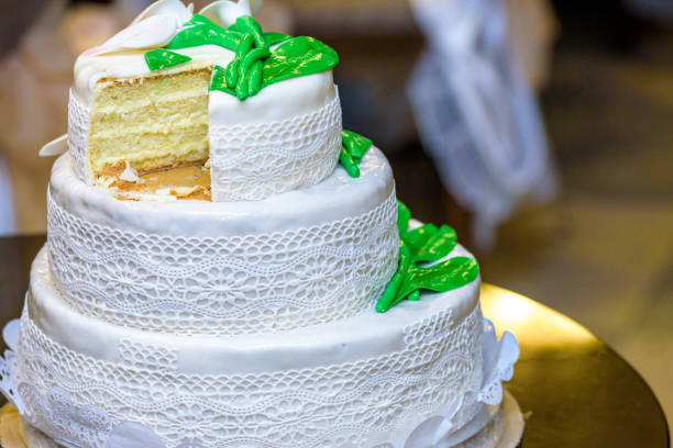 Three-tiered wedding cake is decorated with flowers and stands on the table next to a plate and cutlery.