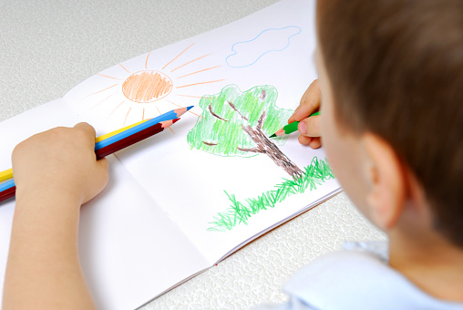 Preschooler drawing using the multicolored pencils