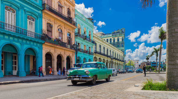 cityscape with american green vintage car on the main street in havana city cuba - serie cuba reportage - old ancient past architecture imagens e fotografias de stock