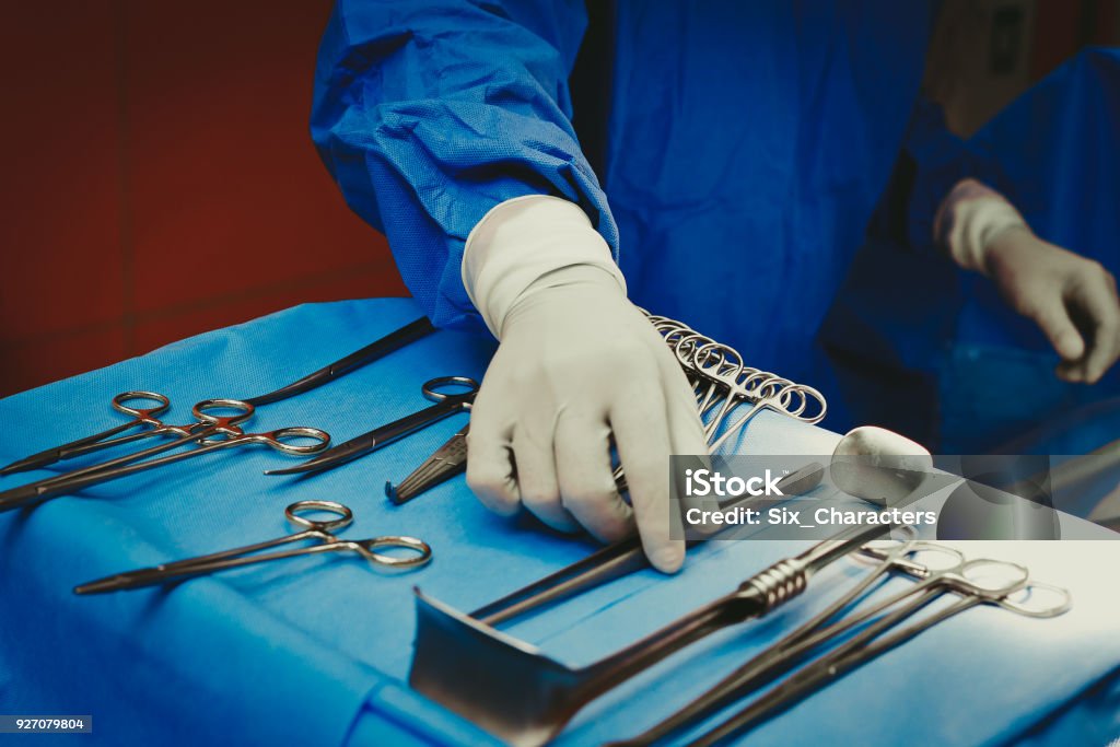 Close-up of surgeons hand holding surgical instruments in the operating room, Surgical tools lying on the table Surgery Stock Photo
