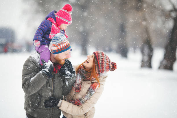 Young family with baby girl having fun in the snow stock photo