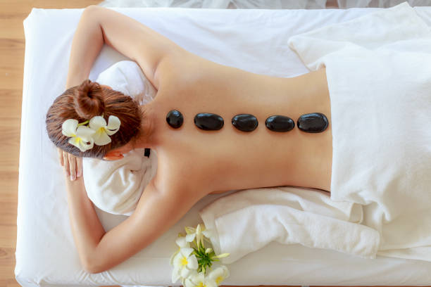 vista superior da bela jovem recebendo massagem com pedras quentes preta em mármore e relaxante no salão spa - massage stones - fotografias e filmes do acervo