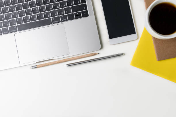istock Top view of office workplace. White desk with copy space. Flat lay view on table with laptop, two cups of black coffee, pens, notebooks and phone. Creative designer concept. 927090914