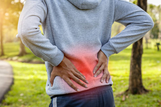 sportler leiden unter rückenschmerzen im park im freien, niedrigere rückseitige schmerz-konzept - pain backache human spine massaging stock-fotos und bilder