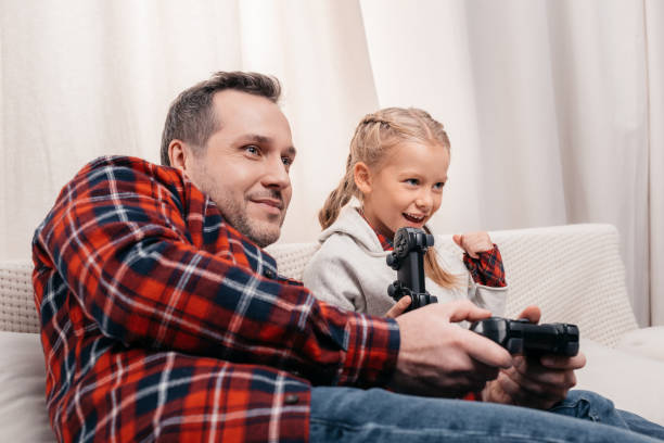 istock father and daughter playing with joysticks 927096814