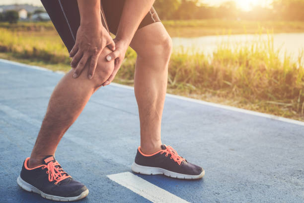 istock Injury from workout concept : Asian man use hands hold on his knee while running on road in the park. Shot in morning time, sunlight and warm effect with copy space for text or design 927097084