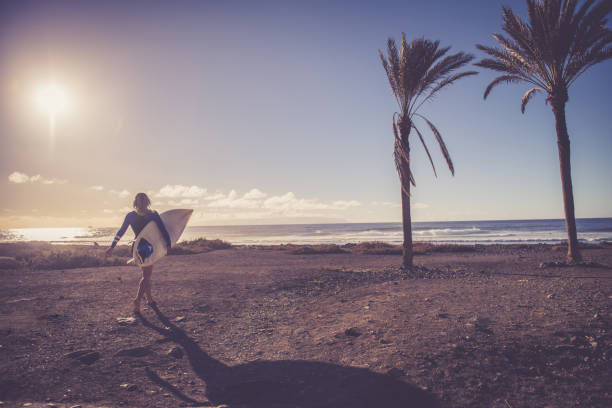 Young female surfer at the beach; Playa Las Americas, Tenerife. Europe / Africa. Nikon D850, All logos removed.