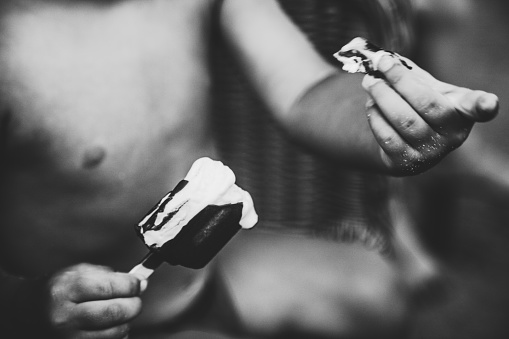 padre pulisce la mano del bambino sporca di gelato en bianco e nero photo