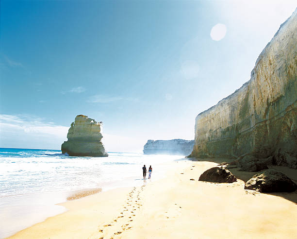 couple walking along a beach. - twelve apostles sea rocks fotos fotografías e imágenes de stock