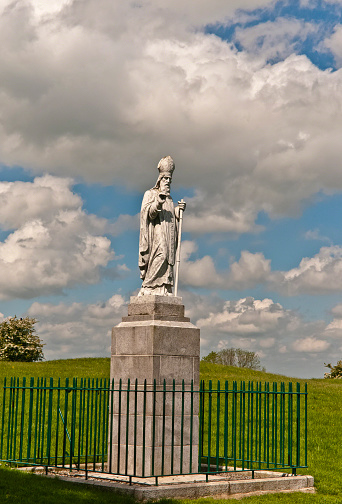 A statue of Saint Patrick fittingly welcomes visitors to the Hill of Tara, County Meath, Ireland.  This statue of cast concrete was an existing statue donated by the Sisters of Charity, moved from an existing installation to the Hill of Tara in the year 2000 AD to replace the previous statue removed in 1992 in a state of disrepair.  The creator is anonymous, the is no plaque or other attribution on or around the statue.  I researched this information March 12, 2018 using internet resources.  My research is attached in an Microsoft Word document submitted with releases. 
 
The original statue was erected on the summit of the Hill of Tara shortly after Catholic emancipation in 1829, commemorated the events of 433AD when St. Patrick lit a bonfire on the nearby hill of Slane on the eve of Easter Sunday.