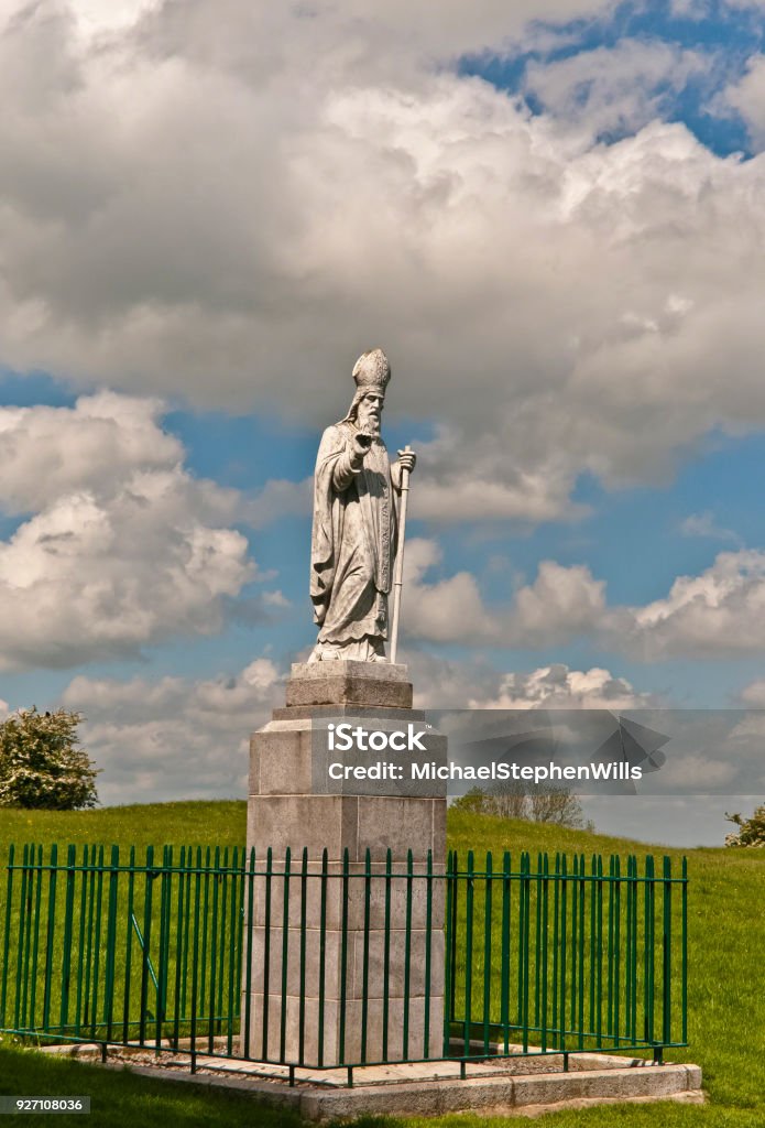 Saint Patrick, Hill of Tara A statue of Saint Patrick fittingly welcomes visitors to the Hill of Tara, County Meath, Ireland.  This statue of cast concrete was an existing statue donated by the Sisters of Charity, moved from an existing installation to the Hill of Tara in the year 2000 AD to replace the previous statue removed in 1992 in a state of disrepair.  The creator is anonymous, the is no plaque or other attribution on or around the statue.  I researched this information March 12, 2018 using internet resources.  My research is attached in an Microsoft Word document submitted with releases. 
 
The original statue was erected on the summit of the Hill of Tara shortly after Catholic emancipation in 1829, commemorated the events of 433AD when St. Patrick lit a bonfire on the nearby hill of Slane on the eve of Easter Sunday. Saint Patrick - Saint Stock Photo