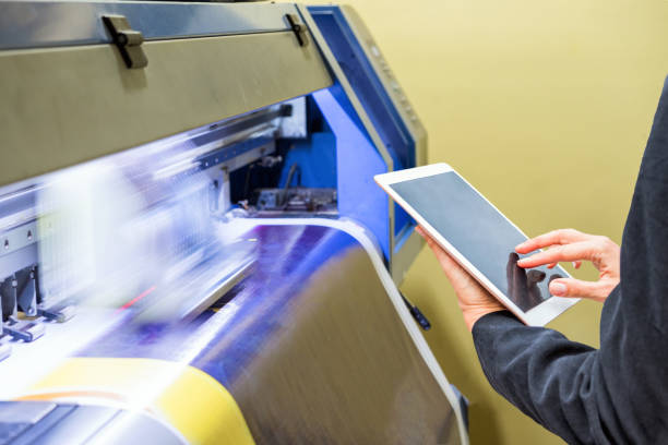 Technician using tablet control with format large inkjet printing blue vinyl Technician using tablet control with format large inkjet printing blue plate digital printing house stock pictures, royalty-free photos & images