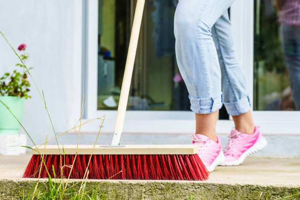 istock Woman using broom to clean up backyard patio 927110360