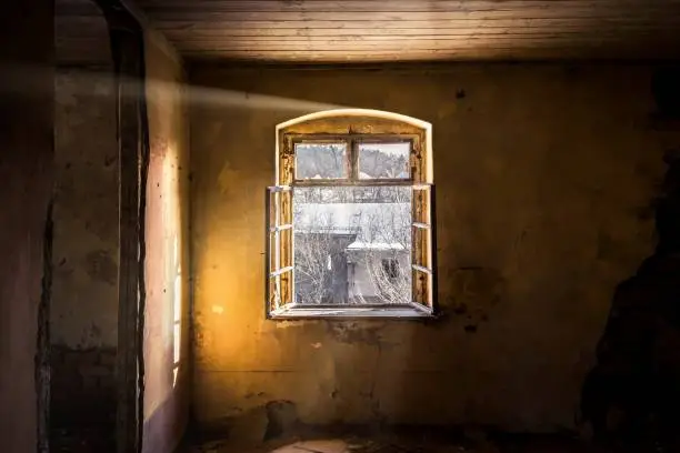 An old dilapidated room with open windows and sunlight