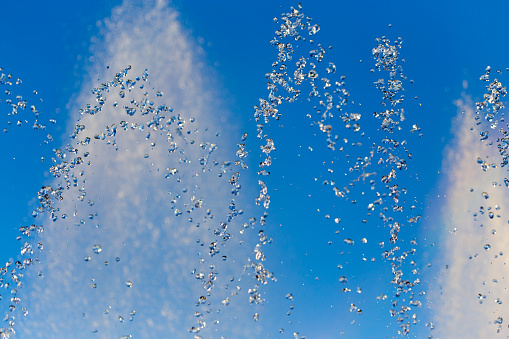 water splashing from the fountain in the background of blue sky .