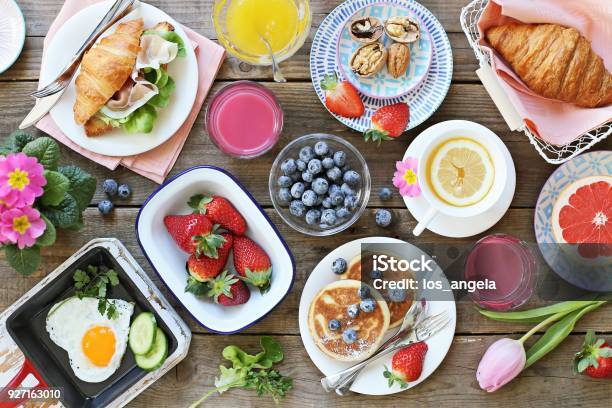 Tabla De Alimentos De Desayuno Establecer Festivo Brunch Variedad De Comida Con Huevo Frito Panqueques Croissants Batido De Frutas Bayas Frescas Y Frutas Foto de stock y más banco de imágenes de Primavera - Estación