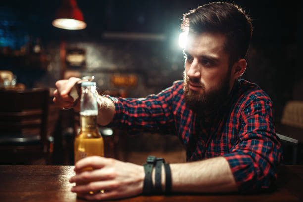 istock Man sitting at the bar counter and opens bottle 927168674