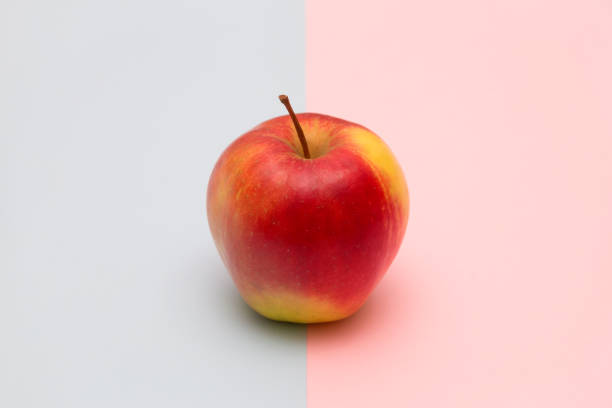 istock One delicious apple on rose quartz and serenity blue background 927179118